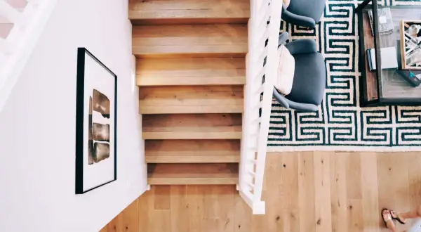 Renovera trappa med matta: en modern trappa i trä med vit balustrad, en grafisk matta och två fåtöljer.