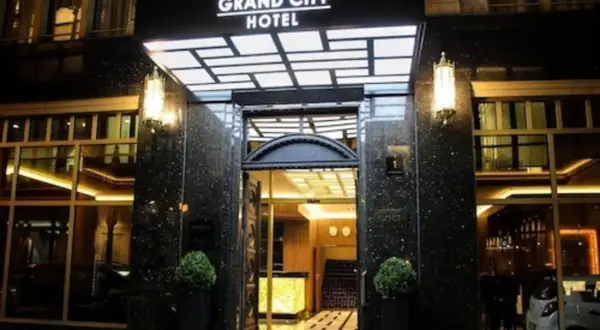 Elegancki **grand city hotel** nocą, z podświetlanym neonem i lśniącym wejściem.