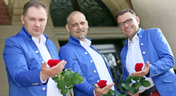 Trzech panów w niebieskich marynarkach, czyli skład zespołu Blue Party, prezentuje czerwone róże.