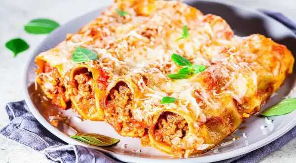Cannelloni ripieni di carne al sugo, gratinati al forno con parmigiano e basilico, un classico della fregnacce ricetta viterbese.