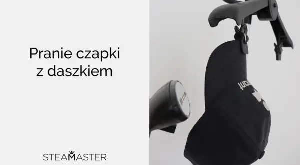 Jak prać czapkę z daszkiem? Czarna czapka zawieszona na wieszaku, obok parownica.