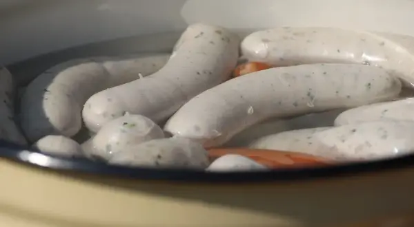 Weiße Würste garen in heißem Wasser. Die Frage "wie lange Wiener kochen" beschäftigt viele Hobbyköche.