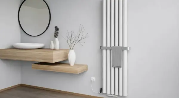 Nowoczesna łazienka z umywalką i lustrem. Obok wertykalny grzejnik aluminiowy czy stalowy z wieszakiem na ręcznik.