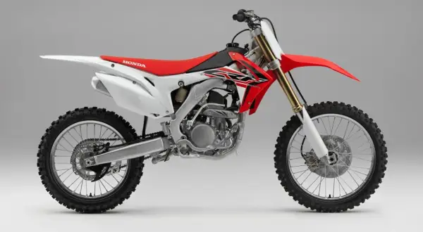 Czerwono-biały motocykl crossowy Honda z widocznym silnikiem i kołami.