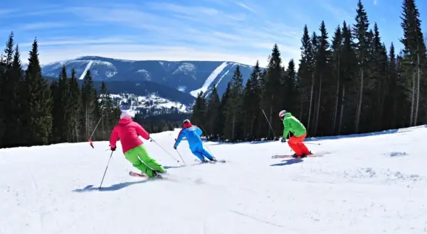 Skifahrer genießen die Pisten in Spindleruv Mlyn. Ein sonniger Tag mit Blick auf die Berge und den Wald.