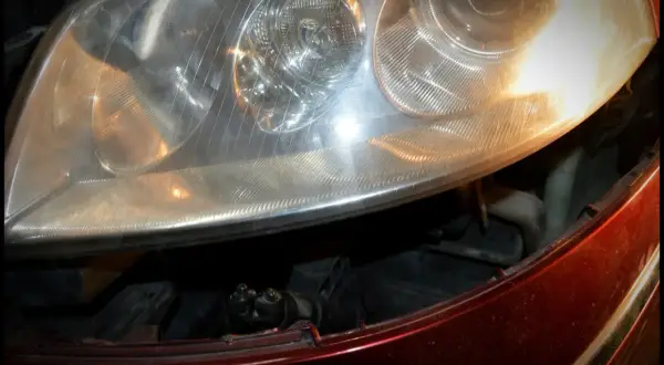 Reflektor Passat B5 FL, widok na żarówki przód. Widać fragment czerwonego lakieru i wnętrze lampy.