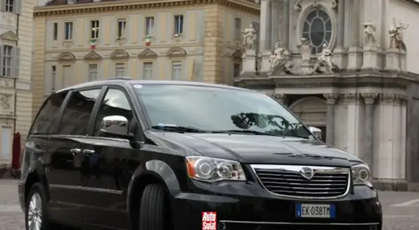 Czarny Lancia Voyager na tle zabytkowej architektury.