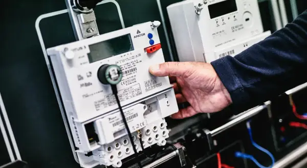 Dłoń manipuluje przy liczniku energii elektrycznej, przygotowując go do przepisania licznika PGE.