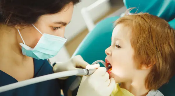 Dentystka bada zęby dziecka, by zapobiec chorobom zębów u dzieci.