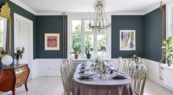 Elegant matsal med dukat bord, kristallkrona och konst. En vacker inspiration för att renovera sekelskifteshus.