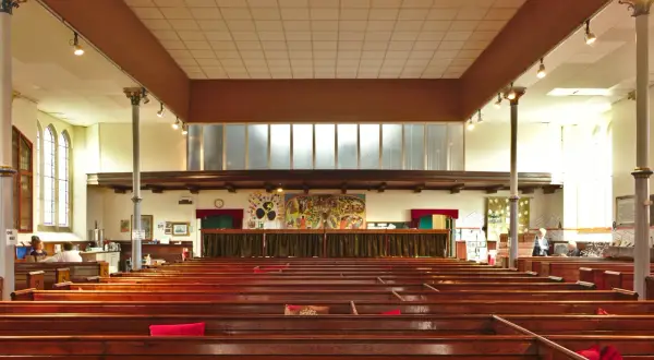 Intérieur d'une église protestante, avec des bancs en bois verni et une fresque colorée au mur. Un lieu paisible pour un baptême chez les protestants.