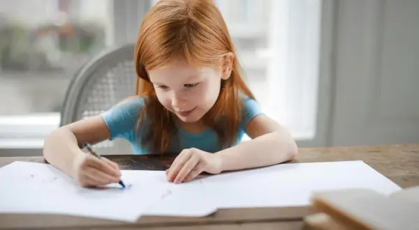 Ruda dziewczynka rysuje. Jej skupienie i zaangażowanie to cechy, które doceni każdy pedagog specjalny, posiadający odpowiednie kwalifikacje.