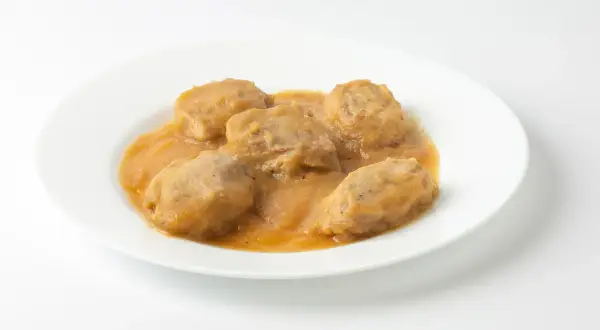 Solomillo de cerdo con manzana en salsa, servido en un plato blanco.
