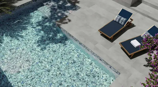 Modernas ideas de piscinas: piscina con mosaico azul brillante, tumbonas y flores moradas.