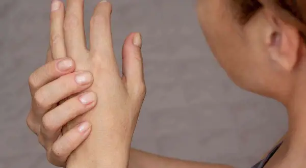 Mano che si tiene, con dita piegate, per alleviare il dolore alle falangi delle mani.