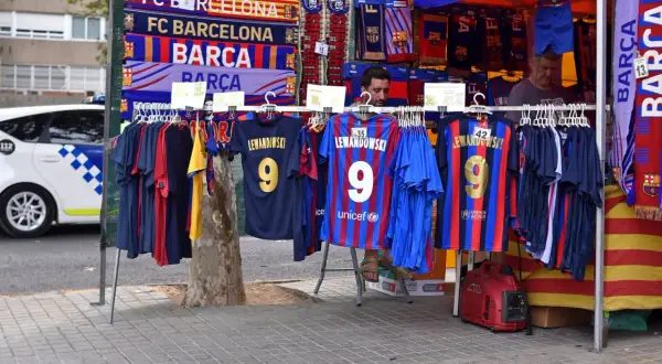 Stoisko z gadżetami FC Barcelona, w tym koszulkami z nazwiskiem Lewandowskiego. W tle widać radiowóz. Polacy w La Liga to już rzeczywistość!