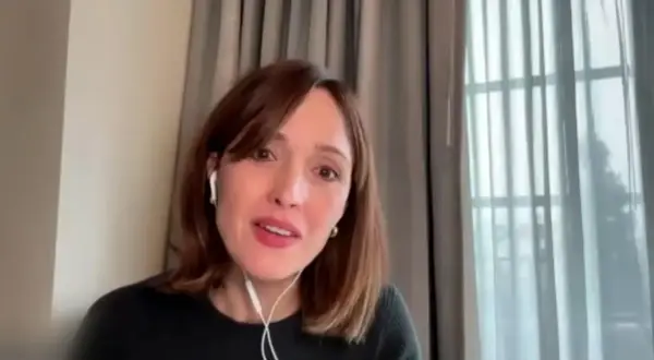 Rose Byrne w jednym ze swoich filmów, w białych słuchawkach, z uśmiechem na twarzy.