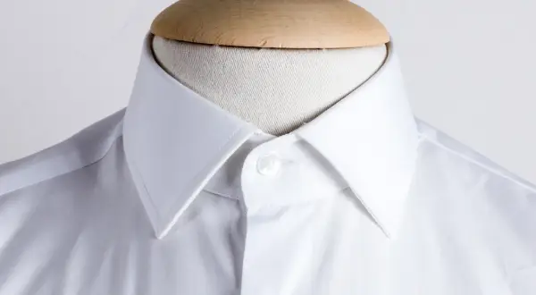 Dettaglio di una camicia bianca con collo italiano, pronta per essere indossata.