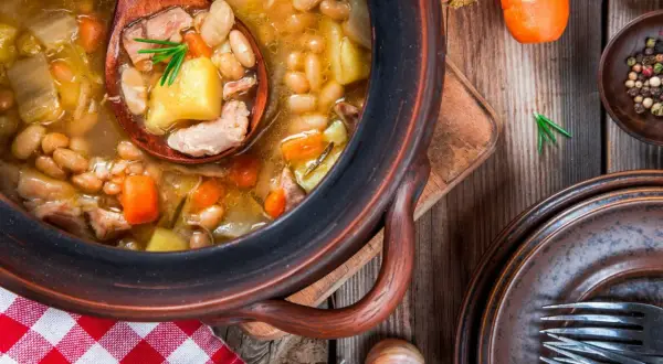 Gęsta zupa fasolowa z kawałkami mięsa, ziemniaków i marchewki. Idealna na chłodne dni, a do jej przygotowania warto dodać czosnek i świeże zioła.
