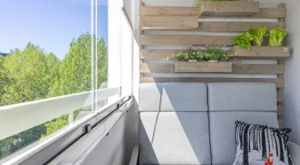 Nowoczesny balkon z szarą sofą i wiszącymi donicami z ziołami i sałatą. Idealne balkon inspiracje dla miłośników zieleni.