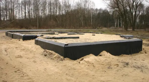 Fundament domu w piasku, otoczony czarną folią, zapewnia prawidłową izolację fundamentów.