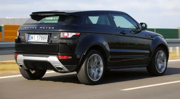Czarny Land Rover Evoque jedzie po drodze, widać jego tylną część i obręcz koła w ruchu.