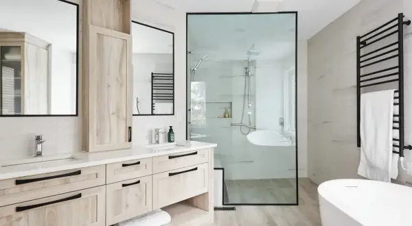 Salle de bain moderne avec double vasque, douche vitrée et baignoire. L'installation plomberie salle de bain est soignée, avec des robinetteries chromées et un sèche-serviettes noir.