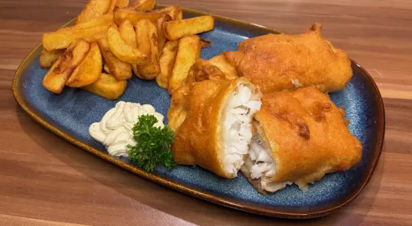 Knuspriges Fish and Chips Rezept: goldbraun frittierter Fisch mit Pommes, dazu Remoulade und Petersilie.
