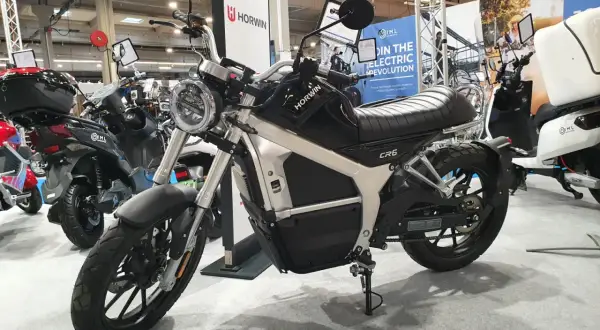 Czarny motocykl elektryczny Horwin CR6 na wystawie, obok innych pojazdów elektrycznych.