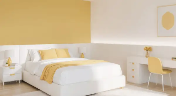 Chambre lumineuse avec un mur de couleur jaune moutarde, un lit blanc, une table de chevet et un bureau.