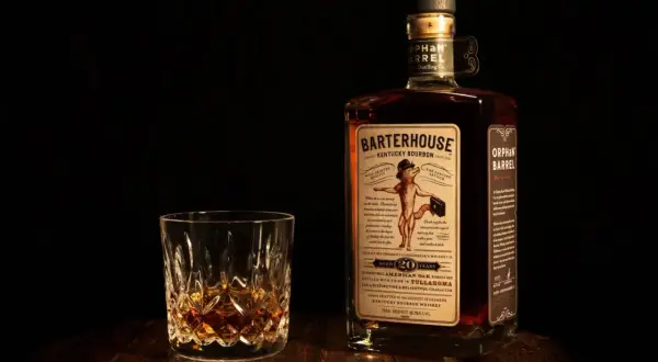 Verre de bourbon ambré et bouteille Orphan Barrel Barterhouse 20 ans. Une dégustation pour apprécier la différence whiskey bourbon.