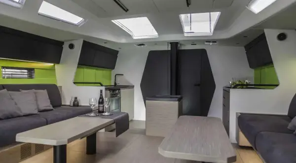 Interni moderni di una nave, con divani, tavoli, cucina e oblò sul soffitto.