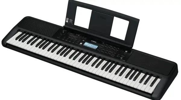 Czarny elektroniczny instrument klawiszowy Yamaha z nutami na stojaku. Idealny do nauki gry.