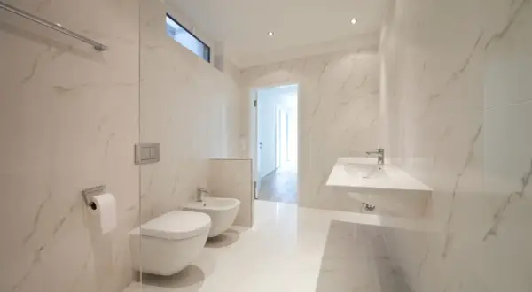 Bagno moderno con bidet e WC sospesi, lavabo a mensola e finiture in marmo. L'altezza scarico bidet è ottimale per un uso confortevole.