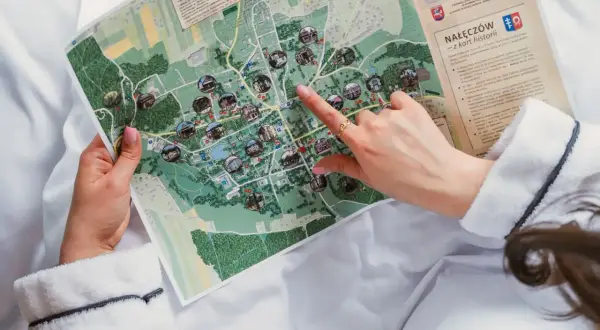 Dłoń wskazuje na mapę z zaznaczonymi atrakcjami turystycznymi.