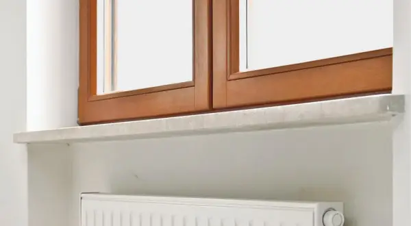 Jasne, oto propozycja:

Kamienne parapety wewnętrzne pod drewnianym oknem, nad białym grzejnikiem.