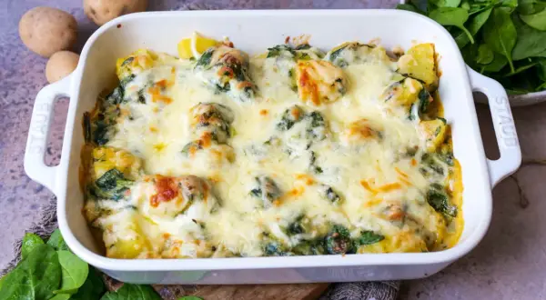 Ein köstlicher Kartoffel-Spinat-Auflauf mit geschmolzenem Käse, bereit zum Servieren. Frische Kartoffeln und Spinat sind die Basis dieses herzhaften Gerichts.