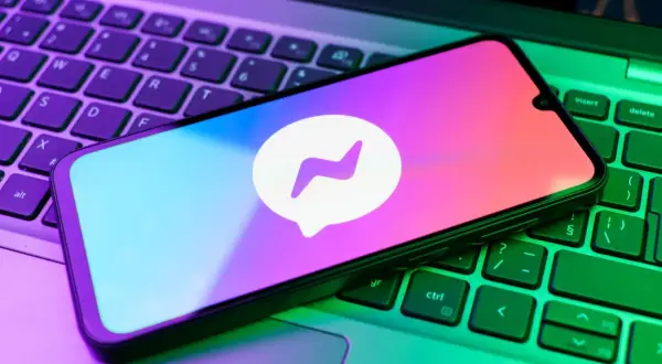 Smartfon z logo Messengera na klawiaturze laptopa. Chcesz wiedzieć, jak zrobic aktualizacje Messengera?
