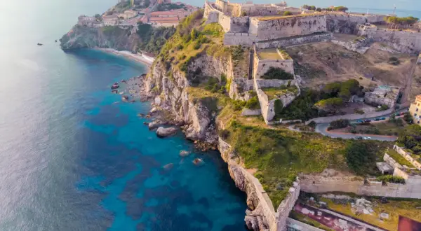 Fortificazioni storiche su una scogliera a picco sul mare turchese, un gioiello delle città della Toscana.