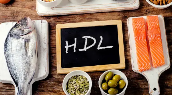 Ryba, łosoś, oliwki, pestki i tabliczka z napisem HDL na drewnianym tle.
