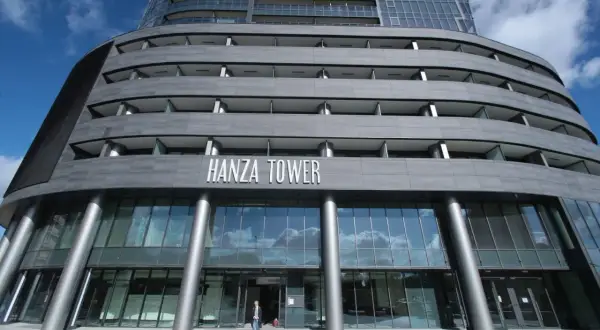 Nowoczesny budynek Hanza Tower z przeszklonym parterem i tarasami.