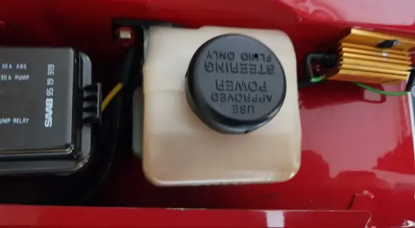 Behållaren för styrservoolja är redo att fyllas på. Bredvid syns en säkringsbox för Saab.