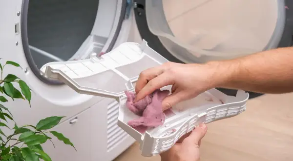 Hände entfernen Flusen aus dem trockner filter reinigen. Regelmäßige Reinigung sorgt für effizientes Trocknen.
