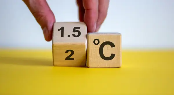 Dłoń obraca kostkę z "2" na "1.5", symbolizując cel paryskiego porozumienia klimatycznego.
