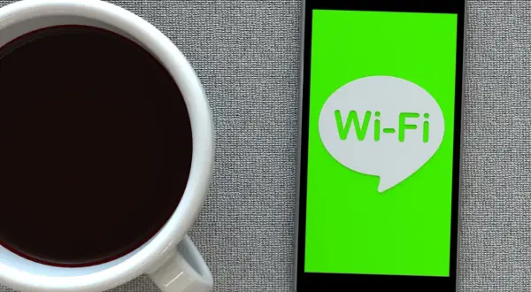 Kawa i smartfon z ikoną Wi-Fi. Zastanawiasz się, jak przyspieszyć internet?