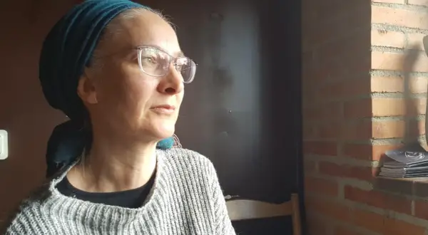 Anna Nachman, med glasögon och en turkos scarf, blickar utåt.
