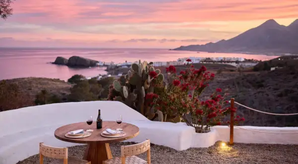 Mesa lista para cenar en el restaurante La Loma Almería, con vistas al mar y un atardecer rosado.
