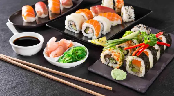 Różnorodne sushi i rolki z łososiem, awokado i warzywami, podane z imbirem, wodorostami i sosem sojowym.