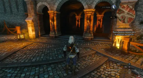 Geralt stoi przed arkadami, szukając skarbu hrabiego Reuvena. W tle widać pochodnie i kamienne mury.