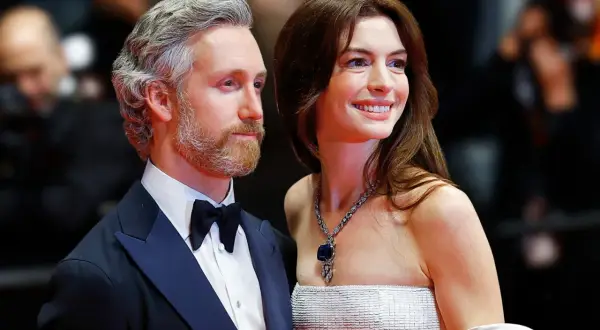 Anne Hathaway z mężem Adamem Shulmanem na czerwonym dywanie. Ona w olśniewającej sukni i biżuterii, on w eleganckim smokingu.